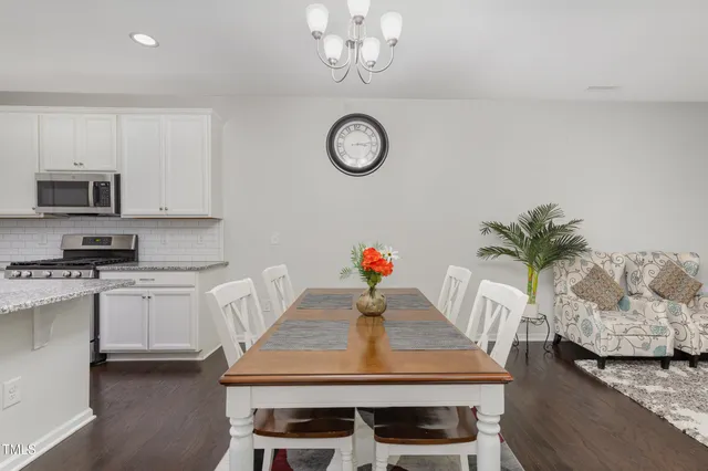 a kitchen with stainless steel appliances granite countertop a stove a microwave a dining table and chairs with wooden floor