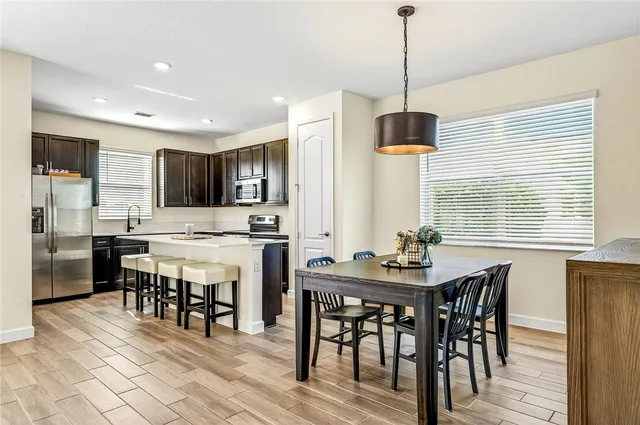 a kitchen with stainless steel appliances a dining table chairs stove and refrigerator
