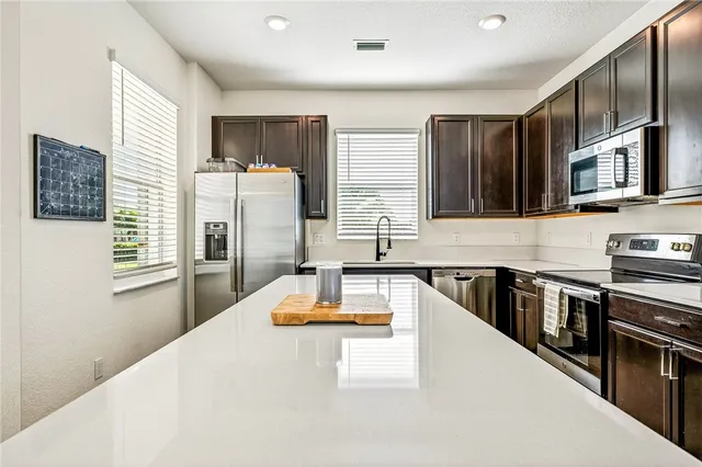 a kitchen with stainless steel appliances granite countertop a refrigerator a stove top oven a sink and dishwasher