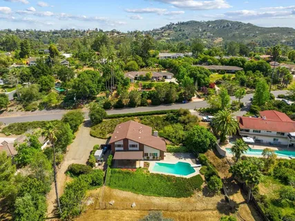 an aerial view of residential houses with outdoor space and trees