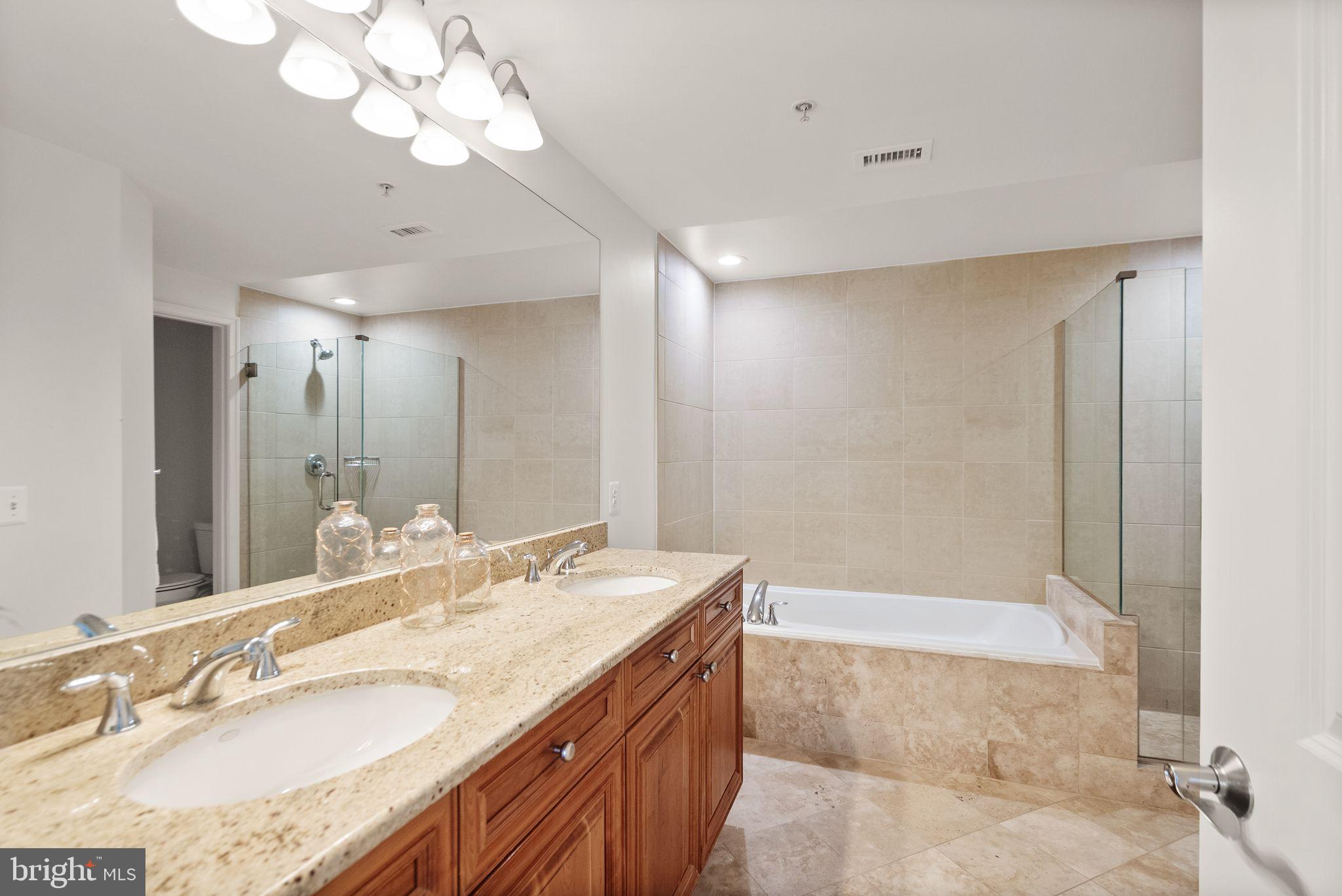 11990 Market Street, Unit 1015 Reston, VA 20190 - Photo 32 of 90 a bathroom with a granite countertop sink a large mirror and a bathtub