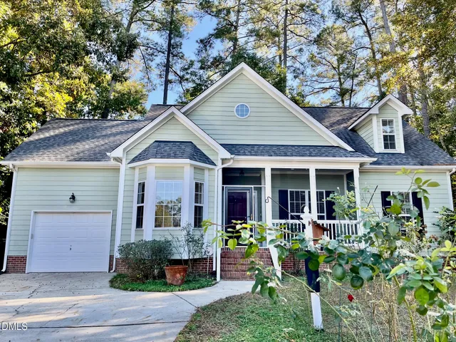a view of a house with potted plants and a large tree