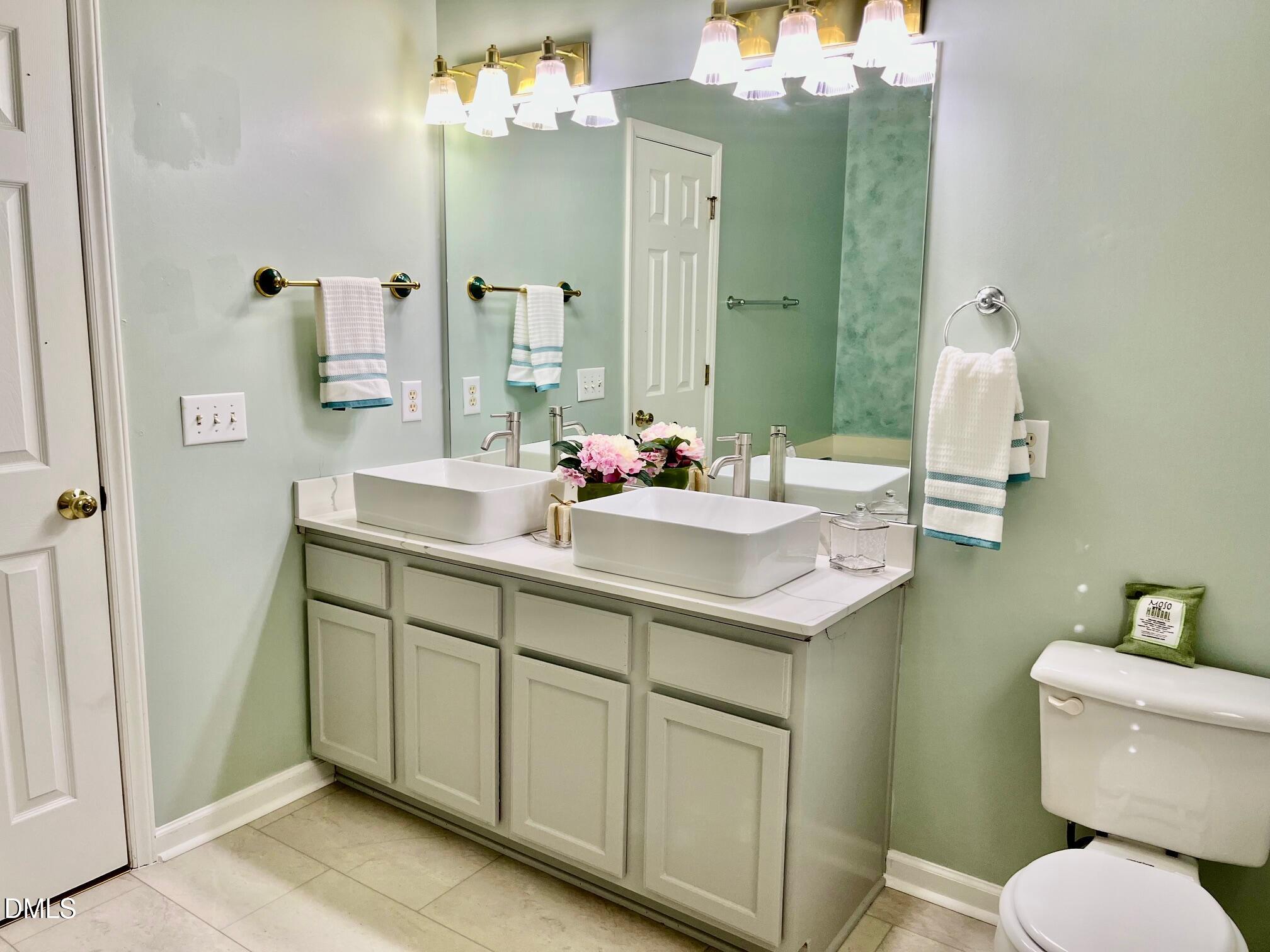 3027 Rennit Court Raleigh, NC 27603 - Photo 12 of 29 a bathroom with a sink and mirror with toilet