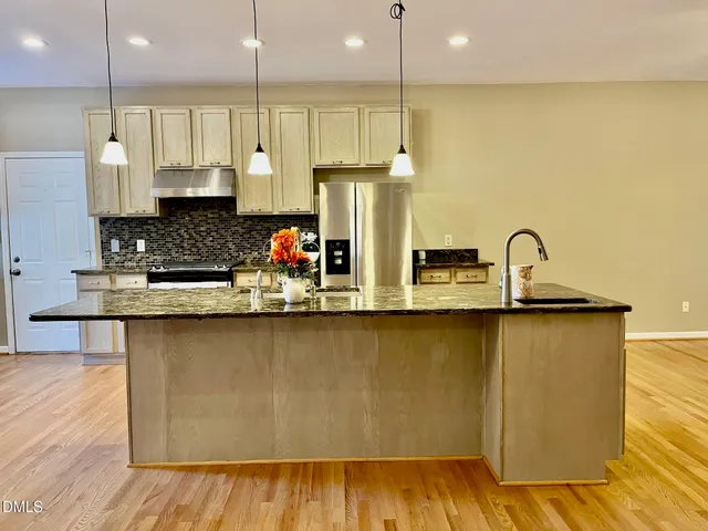 a kitchen with stainless steel appliances granite countertop a sink a stove and a wooden floors