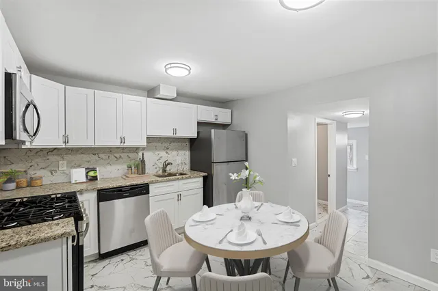 a kitchen with stainless steel appliances kitchen island granite countertop a sink a stove a table and chairs with wooden floor