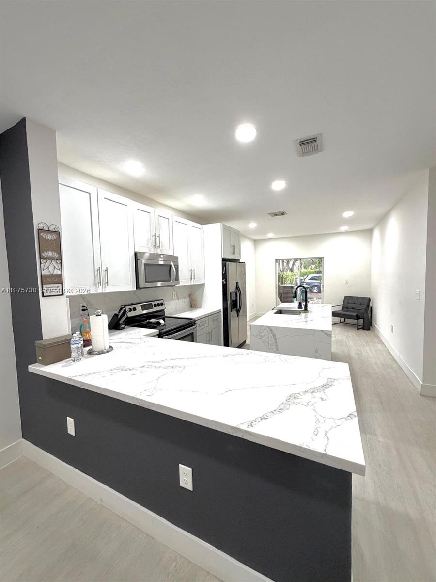 11269 Southwest 231st Lane Miami, FL 33170 - Photo 2 of 19 a large kitchen with kitchen island a sink wooden floor and a counter top space