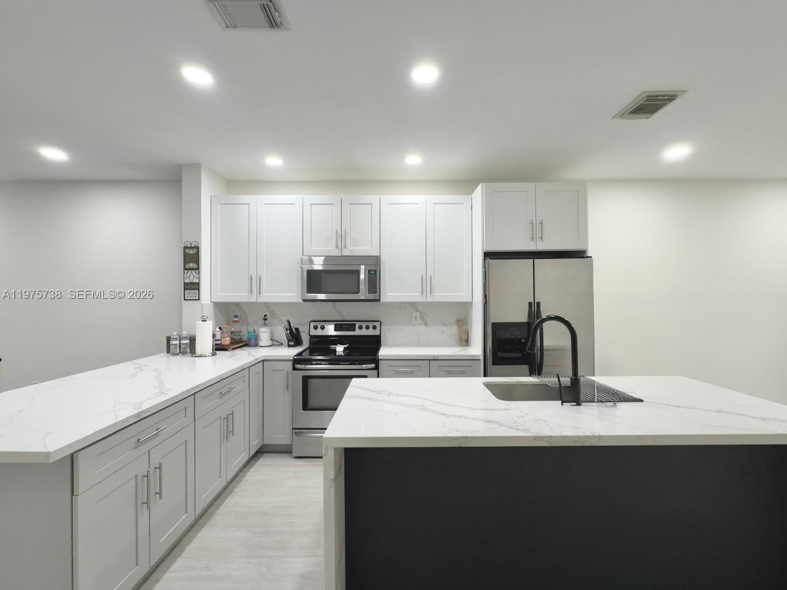 11269 Southwest 231st Lane Miami, FL 33170 - Photo 3 of 19 a kitchen with a sink a stove a refrigerator and white cabinets