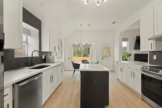a kitchen with stainless steel appliances kitchen island granite countertop a sink stove and cabinets