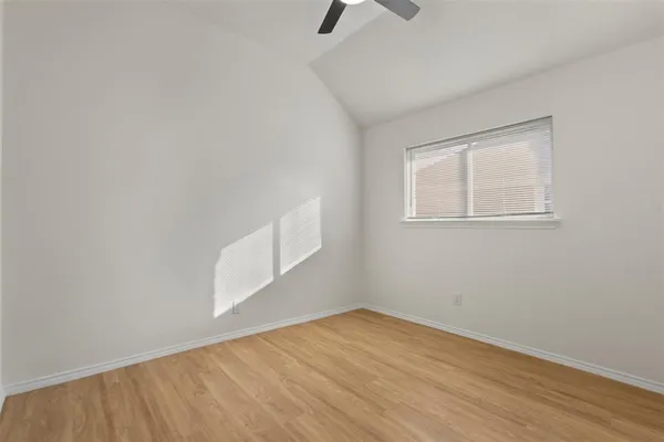 an empty room with wooden floor cabinet and windows