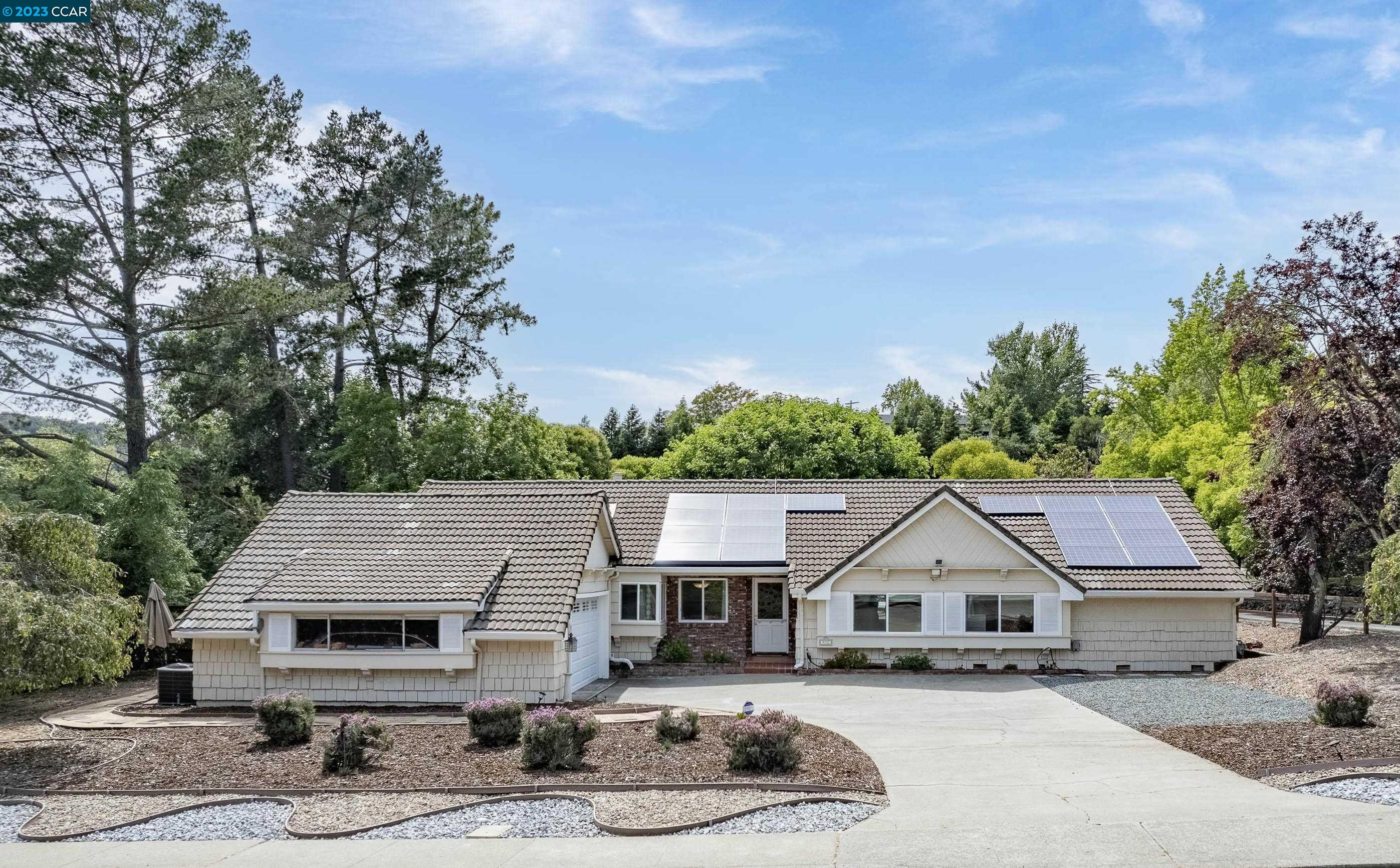 a front view of a house with a garden and tree