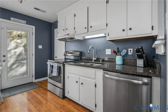 a kitchen with stainless steel appliances granite countertop a refrigerator and white cabinets