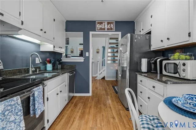 a kitchen with stainless steel appliances granite countertop a stove a sink dishwasher and cabinets with wooden floor