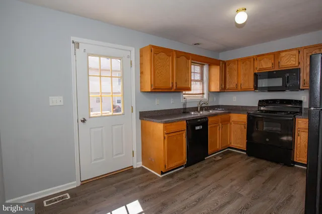 a kitchen with granite countertop wooden floors stainless steel appliances a sink and a window
