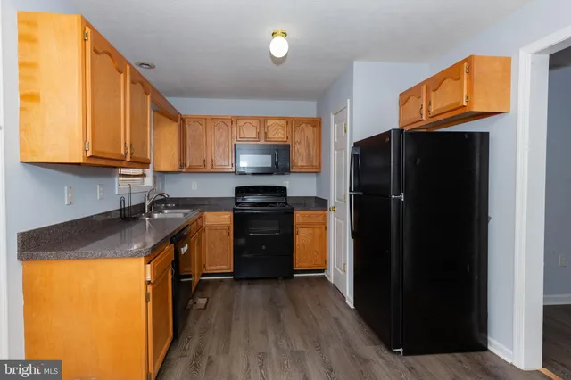 a kitchen with stainless steel appliances granite countertop a refrigerator a sink dishwasher and wooden cabinets with wooden floor