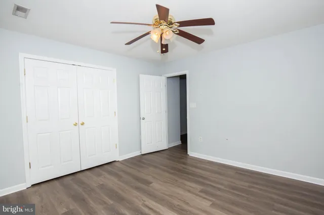a view of an empty room with window a ceiling fan and wooden floor