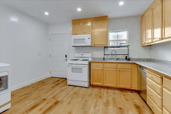a kitchen with granite countertop a sink cabinets stainless steel appliances and a window