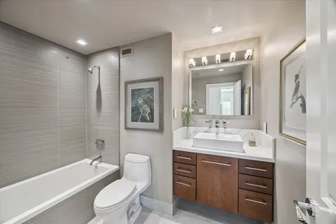 a bathroom with a toilet a sink a tub and mirror