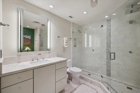 a bathroom with a sink a toilet a mirror and shower