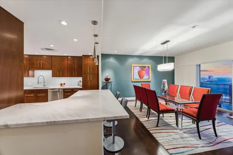 a living room with stainless steel appliances furniture a rug and a kitchen view