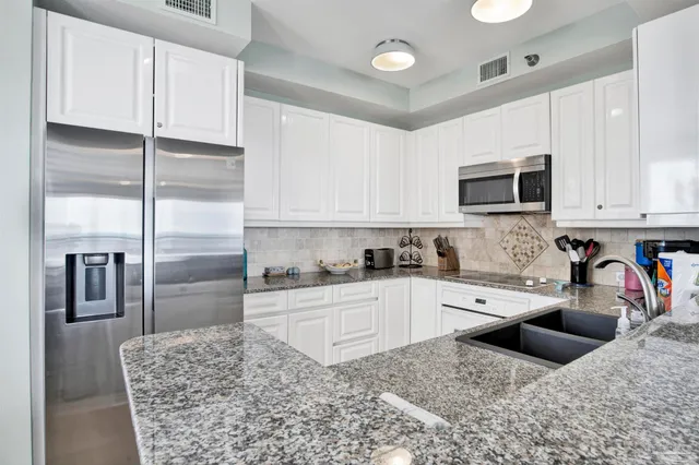 a kitchen with granite countertop a sink a stove and cabinets