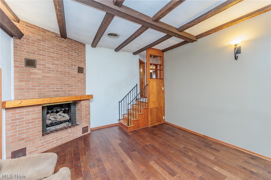 38565 Sugar Ridge Road North Ridgeville, OH 44039 - Photo 11 of 49 Unfurnished living room with dark hardwood / wood-style floors, beam ceiling, and a brick fireplace