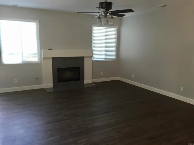 an empty room with wooden floor fireplace and window