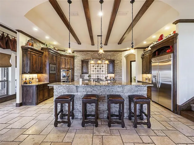 a dining hall with stainless steel appliances granite countertop a table chairs and granite counter tops