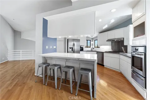 a kitchen with stainless steel appliances a table chairs refrigerator and microwave