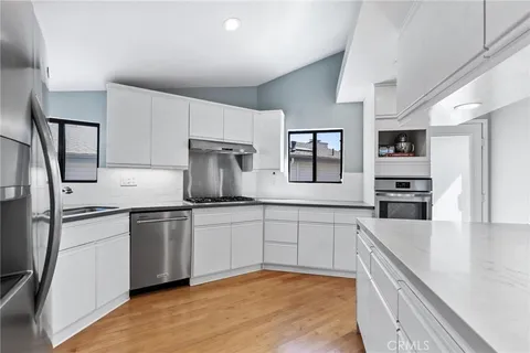 a large kitchen with stainless steel appliances granite countertop a sink and dishwasher a stove top oven with wooden floor