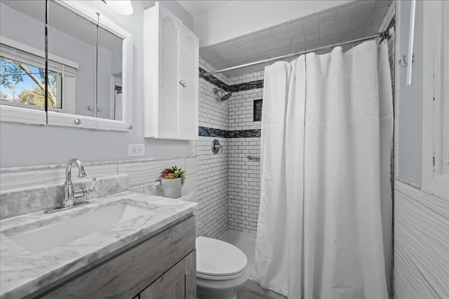 a bathroom with a granite countertop sink toilet and shower