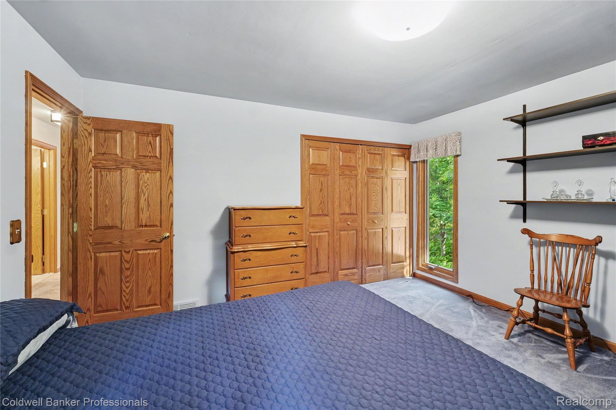 3583 Mitchell Road Metamora, MI 48455 - Photo 36 of 58 Carpeted room with a window providing natural light, featuring wood panel doors, built-in shelving, and light-colored walls