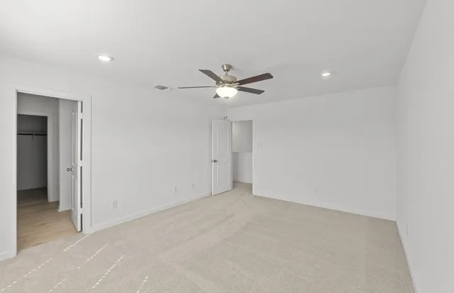 an empty room with closet and ceiling fan