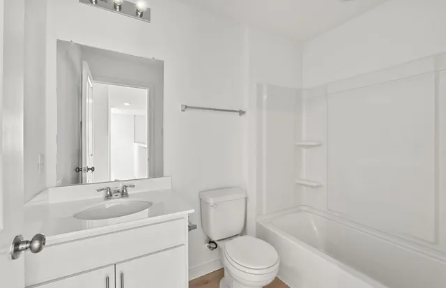 a bathroom with a bathtub shower sink mirror vanity and toilet