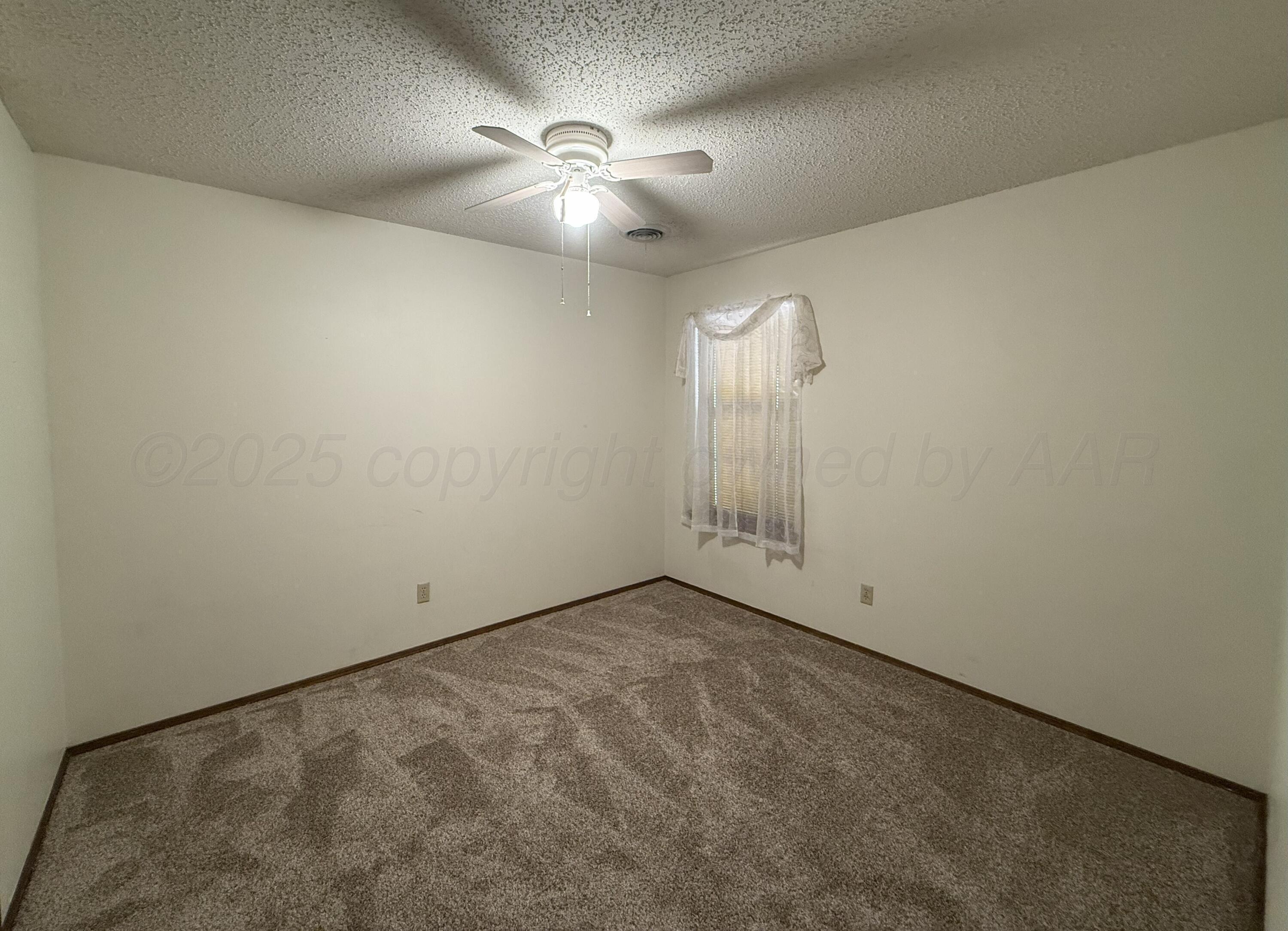 1525 North Nelson Street Pampa, TX 79065 - Photo 11 of 15 an empty room with a chandelier fan and windows