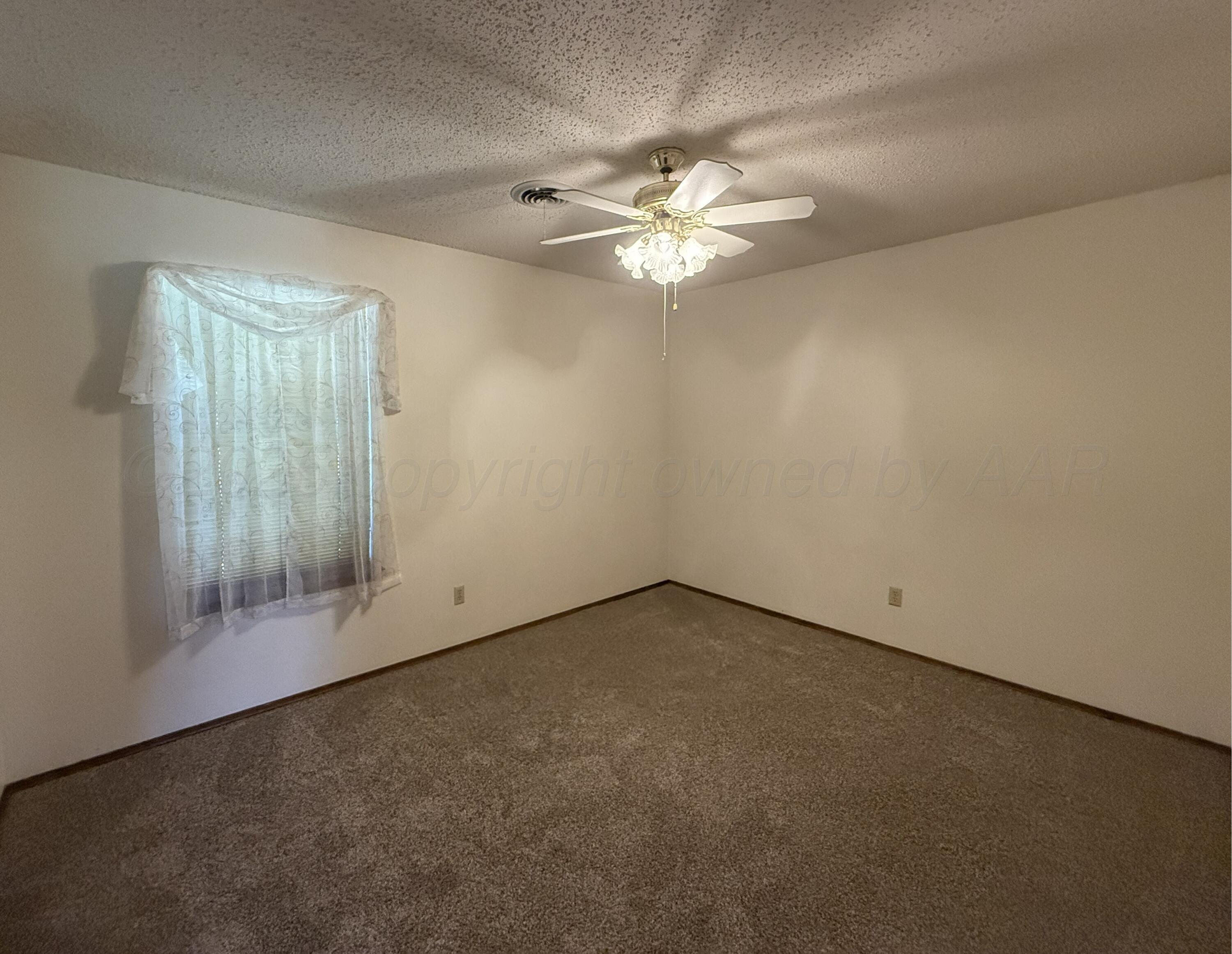 1525 North Nelson Street Pampa, TX 79065 - Photo 5 of 15 an empty room with a chandelier fan