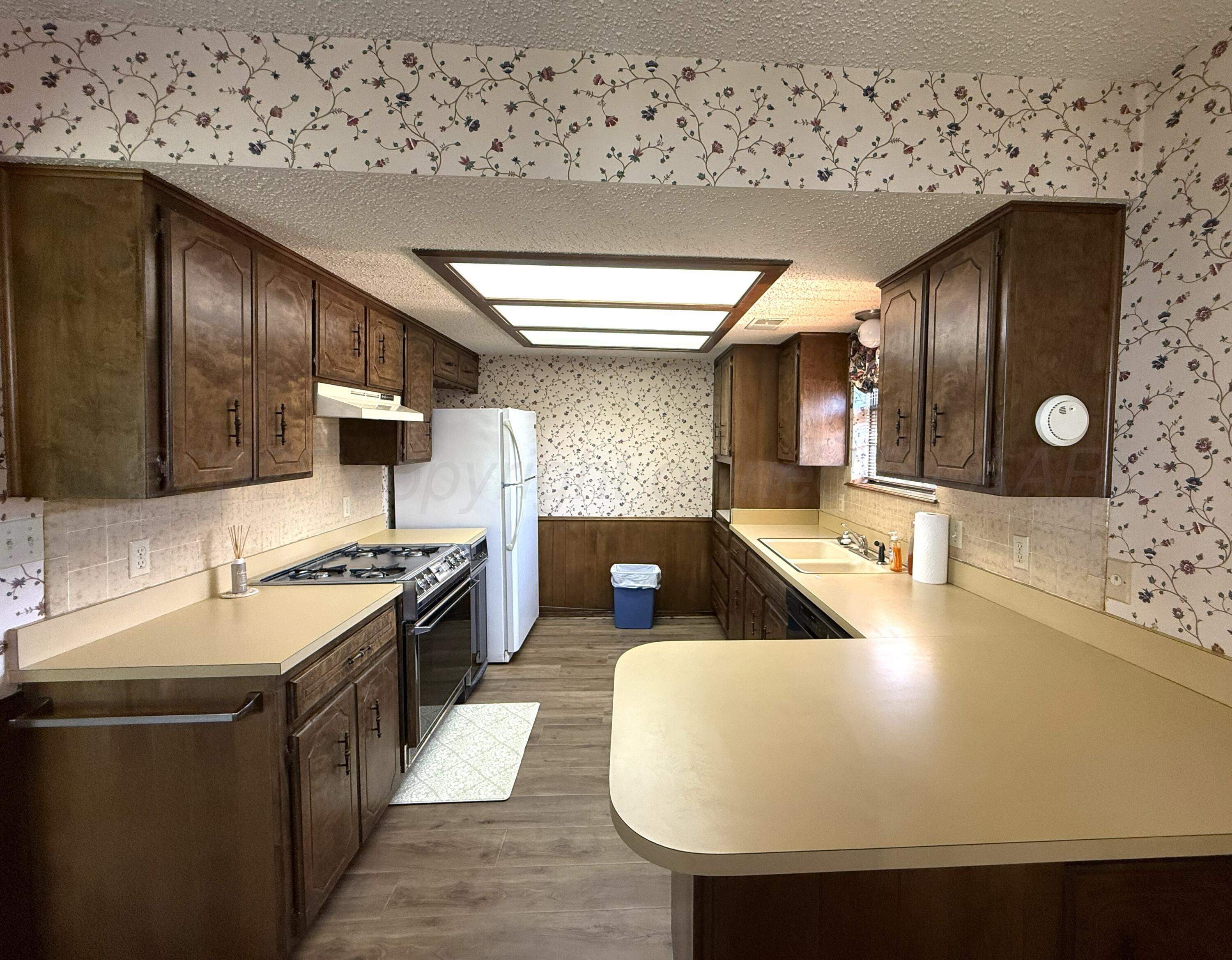 1525 North Nelson Street Pampa, TX 79065 - Photo 7 of 15 a large kitchen with stainless steel appliances a stove a sink dishwasher and a refrigerator with wooden floor