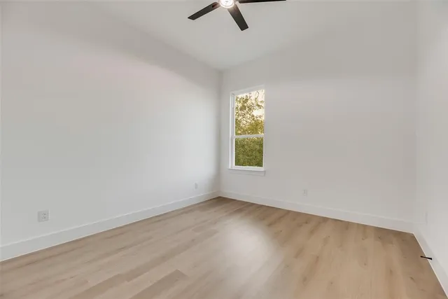 an empty room with windows and ceiling fan