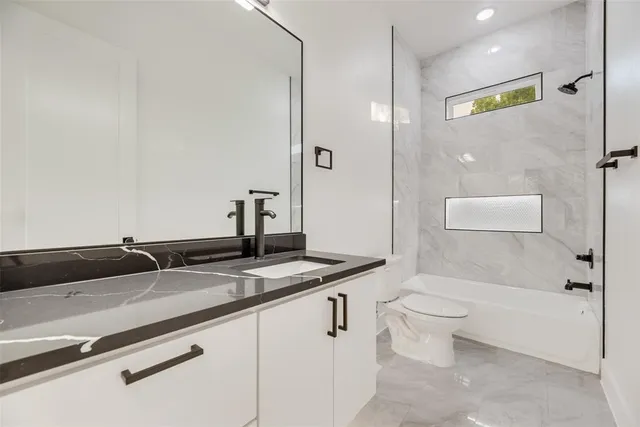 a bathroom with a granite countertop sink a toilet and shower