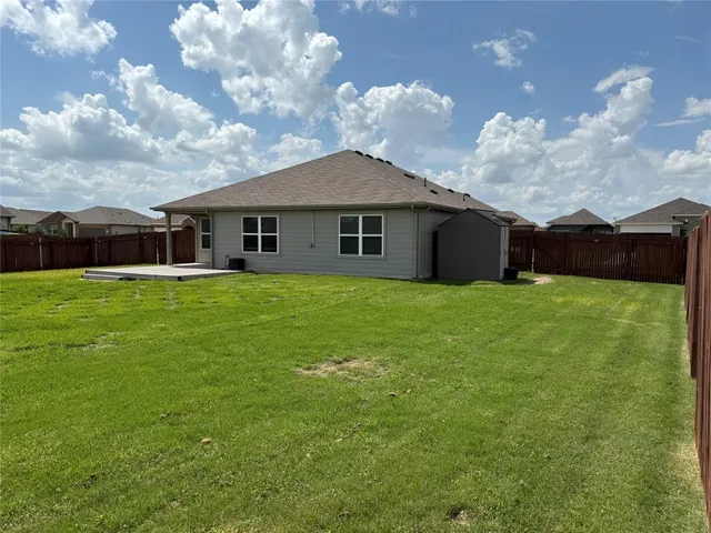 a view of a house with a yard and large trees