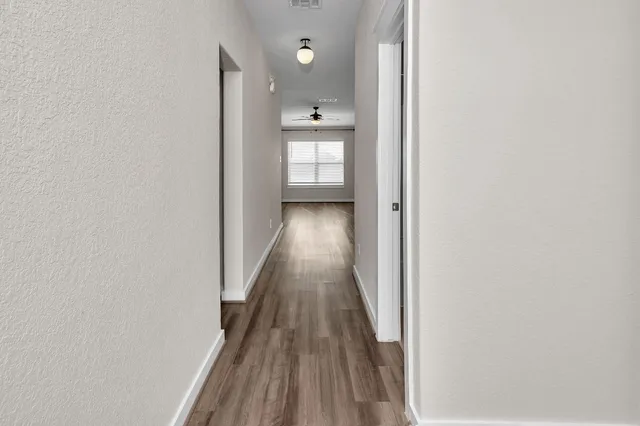 a view of a hallway with wooden floor and a bathroom