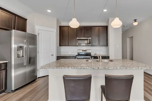 a kitchen with kitchen island a counter space a sink appliances and cabinets