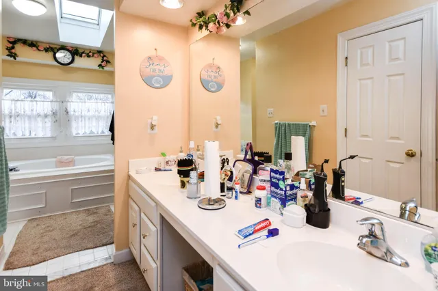 a bathroom with a sink a large mirror and a bathtub next to a window