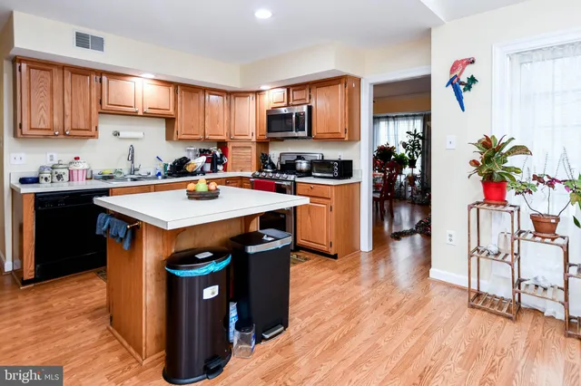 a kitchen with stainless steel appliances granite countertop a refrigerator a stove top oven a sink dishwasher and white cabinets with wooden floor