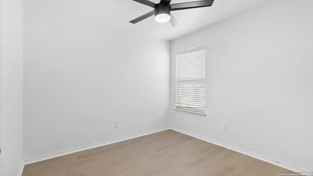 an empty room with a window and a ceiling fan