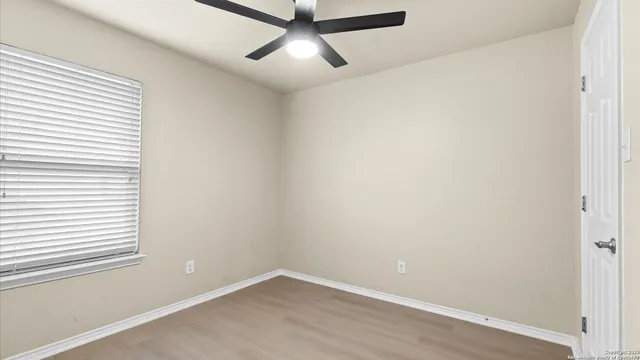 an empty room with a window and a fan