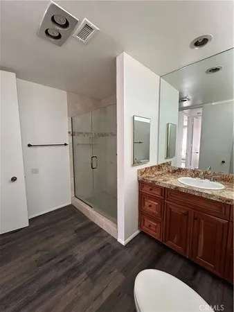a bathroom with a granite countertop sink toilet a mirror and shower