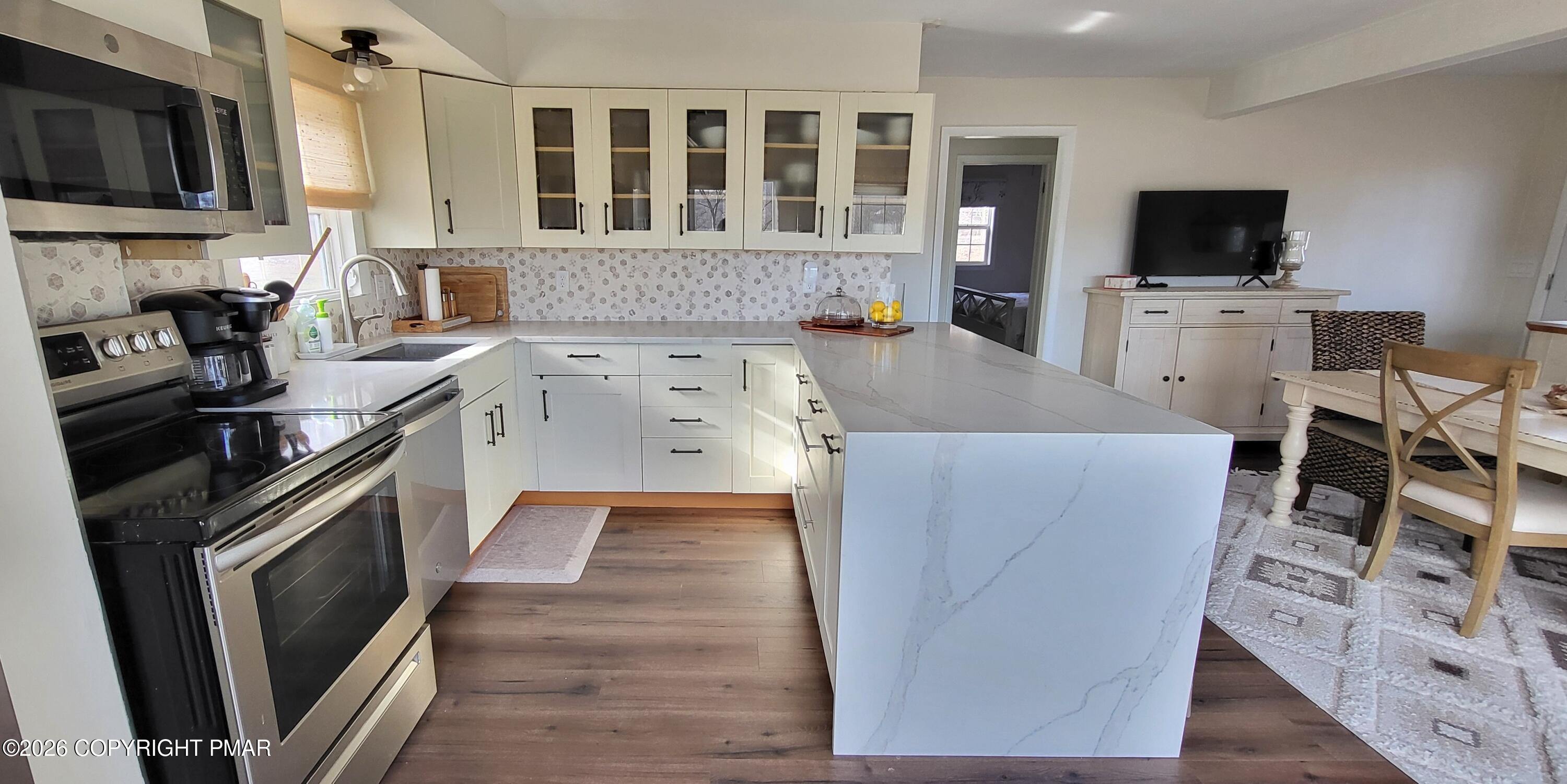 1093 Porter Drive Bushkill, PA 18324 - Photo 7 of 66 a kitchen with stainless steel appliances a stove top oven a sink a dining table and chairs