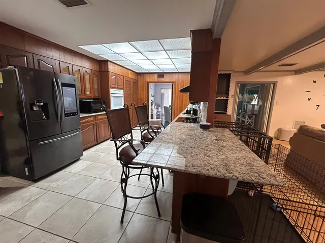 a kitchen with stainless steel appliances granite countertop a table chairs and a refrigerator