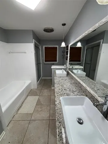 a bathroom with a sink a large mirror and a bath tub