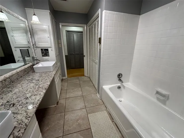 a spacious bathroom with a granite countertop sink a toilet a mirror and bathtub